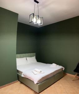 zieloną sypialnię z łóżkiem z 2 ręcznikami w obiekcie Tirana Rooms w Tiranie