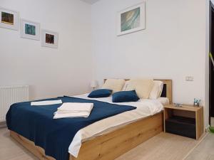 a bedroom with a large bed with a blue blanket at Lora Studio in Mamaia Nord