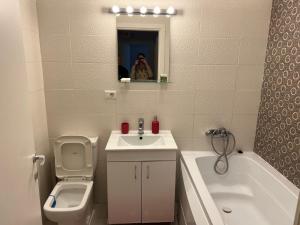 een badkamer met een wastafel, een toilet en een ligbad bij Garsoniera Genova in Otopeni