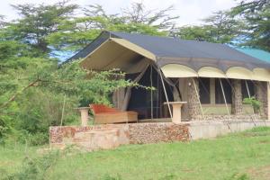 ein Zelt mit einer Bank auf einem Feld in der Unterkunft Orwas maasai Mara safari camp in Kenya in Sekenani