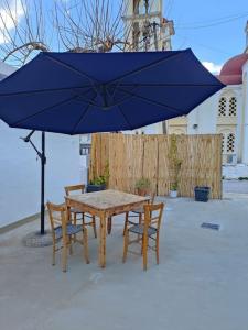 a table and chairs under a blue umbrella at Filia's Countryside House in Chania Town