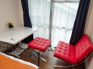 two red chairs and a desk in a room with a window at avanti house姪浜 in Meinohama