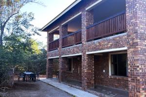 a brick building with a table and a balcony at Melamar Estate in Marloth Park