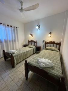 a bedroom with two beds and a ceiling fan at Hotel Garay in San Bernardo