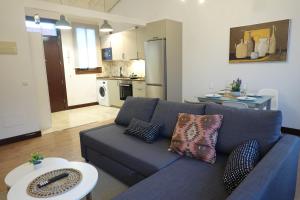 a living room with a blue couch and a kitchen at Apartamento Casa Dalí in Jerez de la Frontera