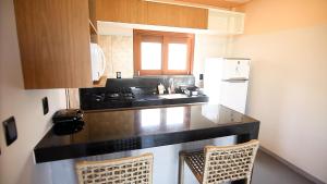 a kitchen with a black counter and a white refrigerator at Pousada Encantos do Coqueiro in Luis Correia +13 photos