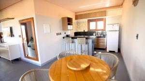a kitchen with a wooden table and some chairs at Pousada Encantos do Coqueiro in Luis Correia