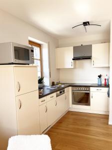 a kitchen with white cabinets and a microwave at Apartment Wohlfühlplatzl - urgemütlich & ruhig in Vogtareuth
