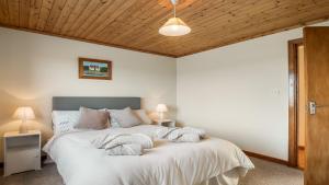 a bedroom with a bed with white sheets and a wooden ceiling at Little Tara, Ballyconneely in Ballyconneely