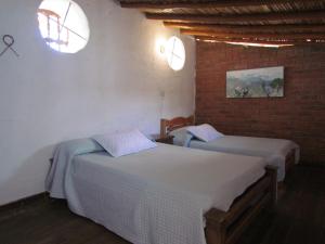 a bedroom with two beds and a brick wall at Casa Yerbabuena- Rustiko in Barichara