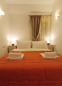 a large bed with orange sheets and white pillows at To Agioklima in Ioannina