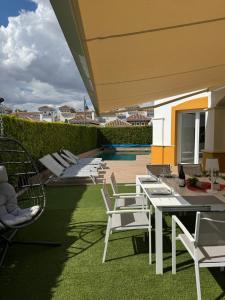 een patio met witte stoelen en tafels en een zwembad bij Villa Molle Mar Menor Golf resort in Torre-Pacheco