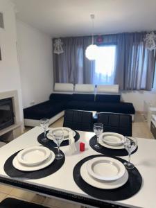 a dining table with plates and wine glasses on it at Grand Monastery Pamporovo Luxury Apartment in Pamporovo