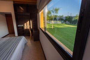 a bedroom with a window with a view of a yard at Estancia Yolanda C1-C3 8Pax - By Inside in Ciudad Lujan de Cuyo