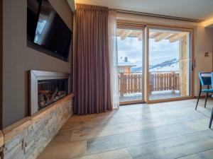 a living room with a fireplace and a large window at Deschana Lodge in Livigno