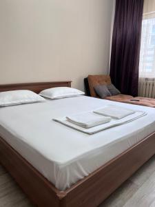 a bed with white sheets and towels on it at 215 Рядом с Байтереком для 1-5 чел с 2 большими кроватями и диваном in Astana