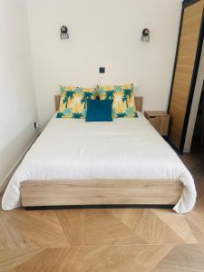 een slaapkamer met een groot wit bed met blauwe kussens bij Maisonnette indépendante avec jardin privatif vue Sainte Baume in Nans-les-Pins