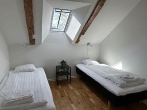 2 camas en una habitación blanca con ventana en Innerstan nya lägenheter Södramurgatan 45b, en Visby