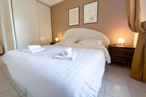 Un dormitorio con una cama blanca con toallas. en St Roch 2 - Appart 300 m de la Gare, clim, terrasse, garage en Antibes