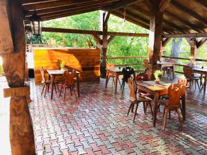 un restaurante con mesas y sillas de madera en un pabellón en Pensiunea Ioana en Borşa