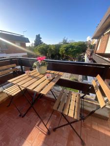 una mesa de madera y bancos en el balcón en Sunbath House Pisa - Free Parking - Near Pisa Center, en Pisa