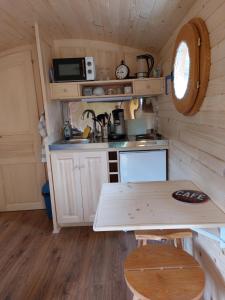 una pequeña cocina con mesa en una casa pequeña en Roulotte ZEN, 