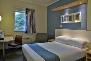 a hotel room with a bed and a desk and a window at Road lodge Hotel Cape Town International Airport -Booked Easy in Cape Town