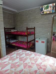 a bedroom with two bunk beds and a tv at Pousada Linda Vista in Domingos Martins