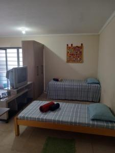 a living room with two beds and a television at Pousada Villa Argos Guesthouse in Piracicaba