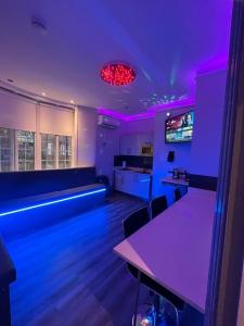 une chambre avec des lumières violettes et des tables ainsi qu'une cuisine dans l'établissement 19 Rodney Street Apartments, à Liverpool
