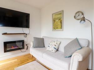 a living room with a white couch and a tv at Lapwing in Perranporth