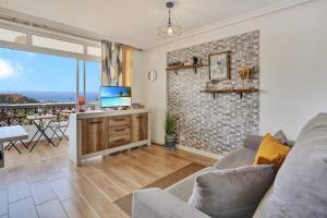 a living room with a couch and a table with a television at Margherita House Tenerife, Wonderful Ocean View in Palm-mar