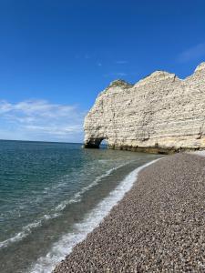 a rocky beach next to the ocean with a rock wall at Villa Roc Vaudieu - Charmante maison de pêcheurs in Étretat