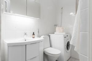 ein weißes Bad mit einem WC und einer Waschmaschine in der Unterkunft Charming Flat in Design District in Helsinki + 30 Fotos