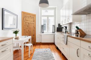 a kitchen with white cabinets and a table and a desk at Charming Flat in Design District in Helsinki