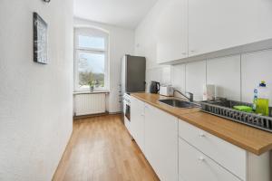 cocina con armarios blancos y suelo de madera en home2stay Apartmenthaus Halle Zentrum Parking,Kitchen,Wifi ***, en Halle an der Saale