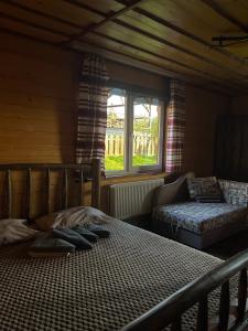 a bedroom with a bed and a couch and a window at Khatky Na Penkakh in Vorokhta