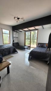 a bedroom with two beds and a room with windows at Villa Monarca, Hermosa Casa cerca a Villa de Leyva in Villa de Leyva