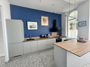 uma cozinha com armários brancos e uma parede azul em Les Lutins - sur la plage em Wimereux