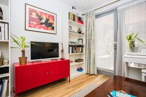 a red entertainment center in a living room with a tv at Beautiful 1 Bedroom in The Heart of Bethnal Green in London