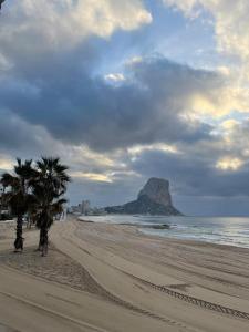 a beach with two palm trees and a mountain at Apartamento Miró in Calpe