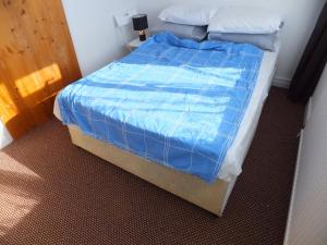 a bedroom with a bed with a blue comforter at Exceptional Rated 10, 15 mins from East Croydon to Central London, Gatwick - Spacious, Sleeps up to 16 plus Cot - Free WiFi, Parking - Next to Lloyd Park, Great for Walkers - Ideal for Contractors - Families - Relocators in Croydon