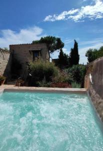 une grande piscine d'eau en face d'une maison dans l'établissement Les chambres du Mas Peu del Causse, 