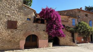un bâtiment avec des fleurs violettes sur son côté dans l'établissement Les chambres du Mas Peu del Causse, 