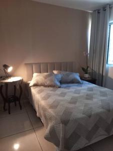 Un dormitorio con una cama y una mesa con una lámpara. en Cantinho Côte d'azur Maceió, en Maceió