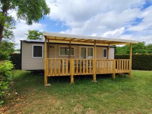 uma pequena casa com um alpendre e um deque em Flower Camping Les Mijeannes em Rieux-de-Pelleport