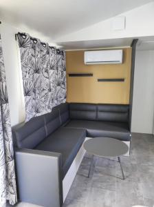 un sofá y una mesa en una habitación en Flower Camping Les Mijeannes en Rieux-de-Pelleport