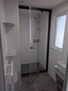 a bathroom with a shower with a glass door at Flower Camping Les Mijeannes in Rieux-de-Pelleport