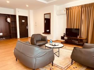 a living room with leather chairs and a tv at Hotel Mayto in Thimphu