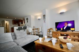 a living room with a couch and a flat screen tv at Bournemouth Hot Tub & Sauna Holiday Let in Bournemouth
